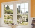 A pair of classic grid-style windows in a warmly decorated interior, looking out to a garden