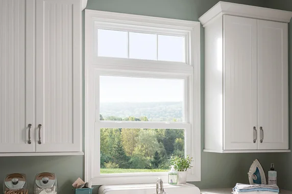 A stylish kitchen with a large double-hung window framed by white cabinets